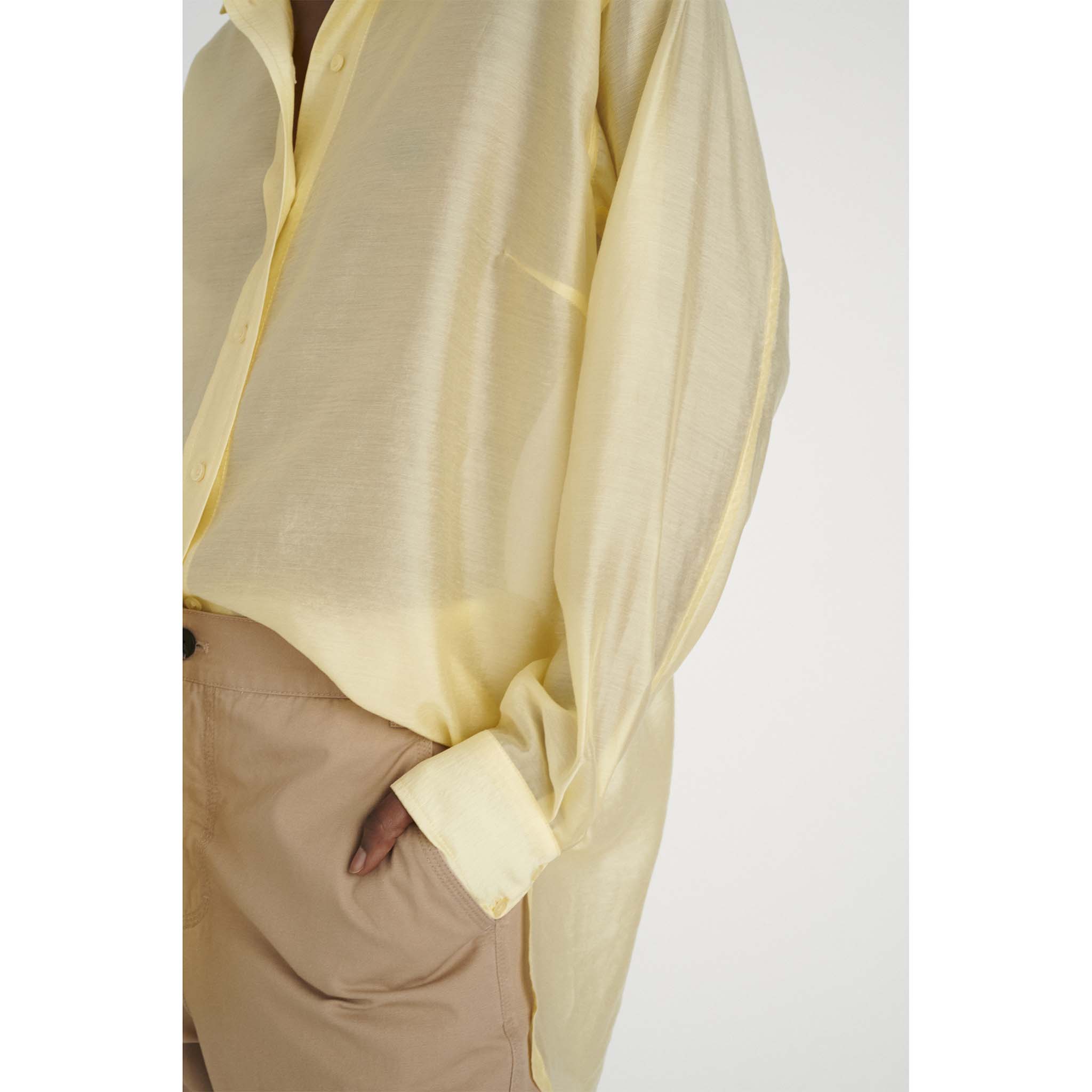 In Wear. Keltainen, hieman kiiltäväpintainen, läpikuultava naisten väljä paitapusero. Lähikuva mallin päällä.