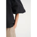 In Wear, naisten musta pusero. Näyttävät, isot puhvihihat. Niskassa solmittavat nauhat ja selkä on avoin. Lähikuva mallin päällä.